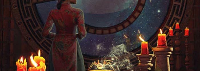 A woman stands with her back to the viewer looking out of a window into space. Bots and candles and brews on a table in front of her.